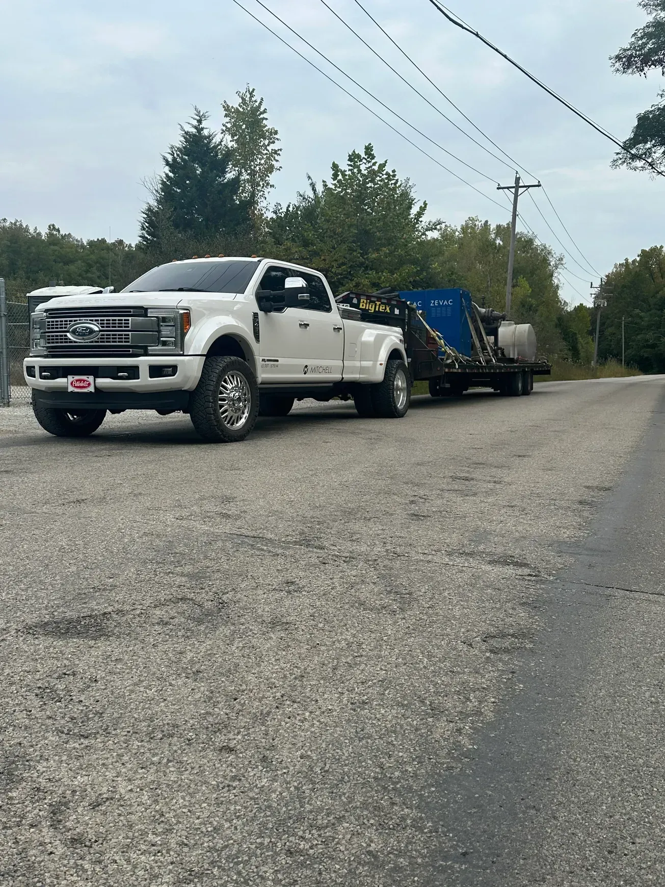 A white truck is parked on the side of the road next to a trailer.
