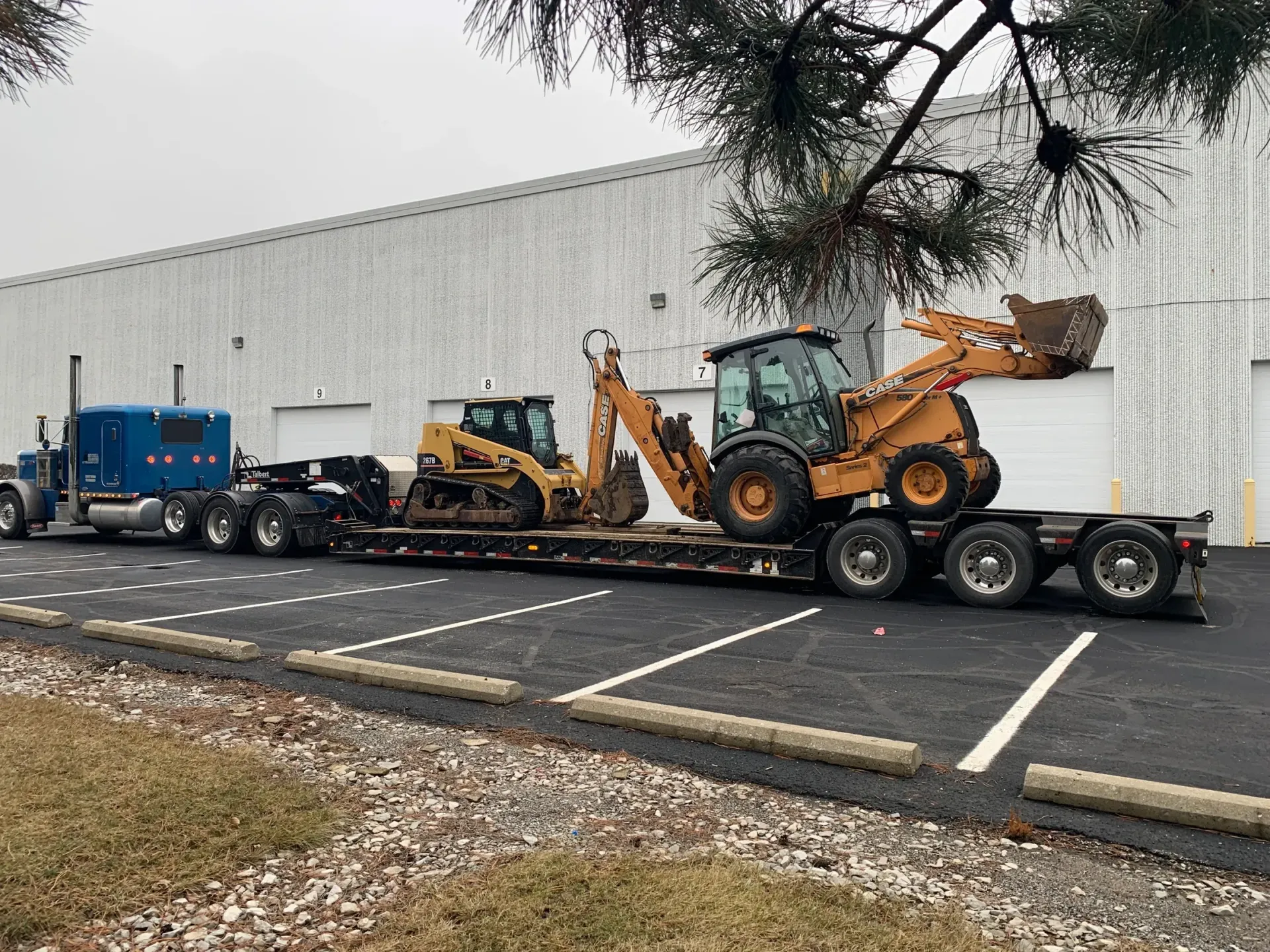 A semi truck is carrying a bulldozer and a backhoe on a trailer.