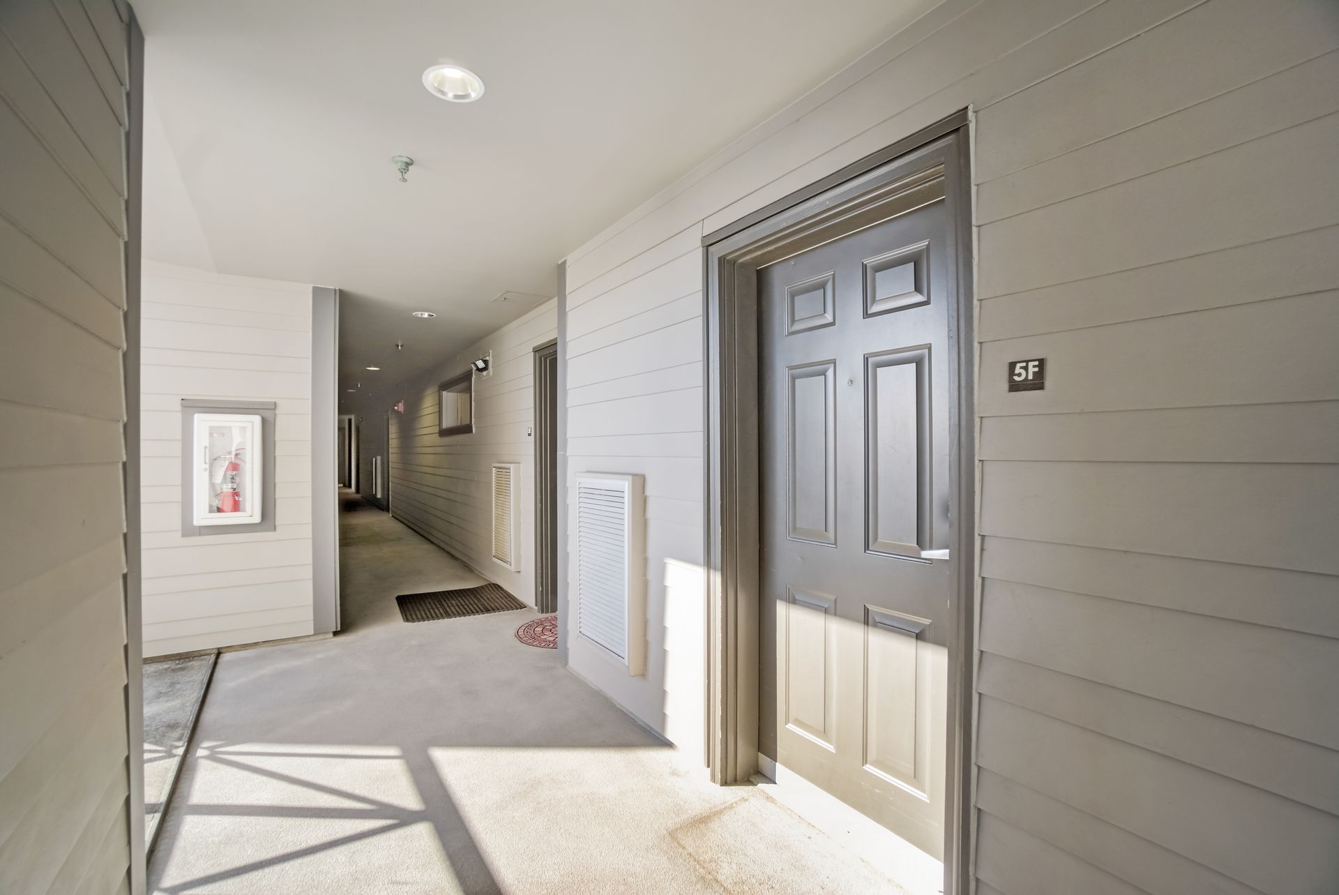 A hallway with a gray door and a picture on the wall.