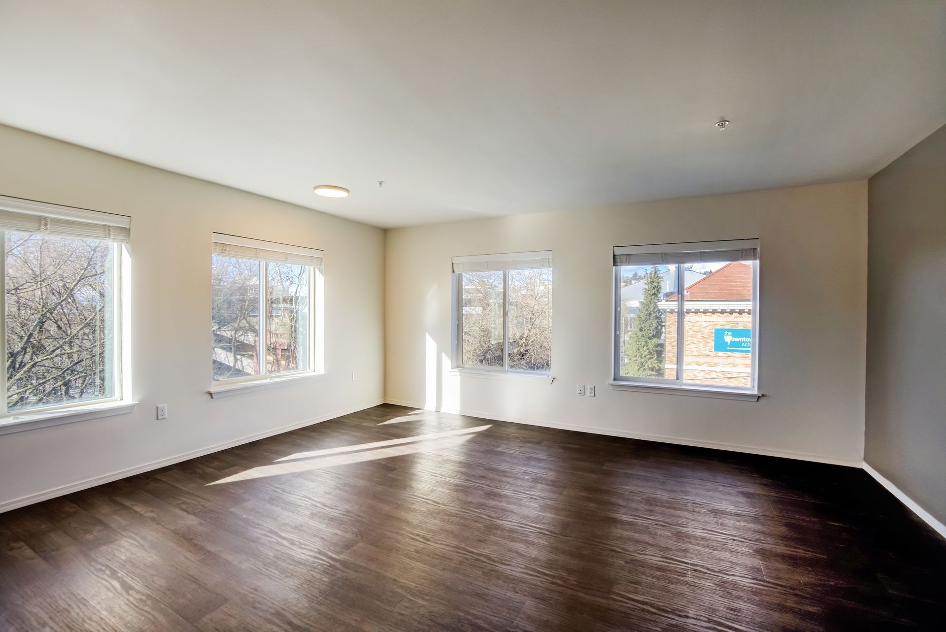 An empty living room with hardwood floors and lots of windows.