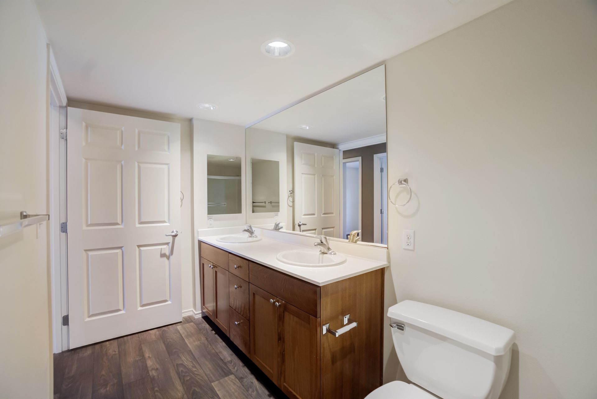 A bathroom with two sinks , a toilet and a large mirror.