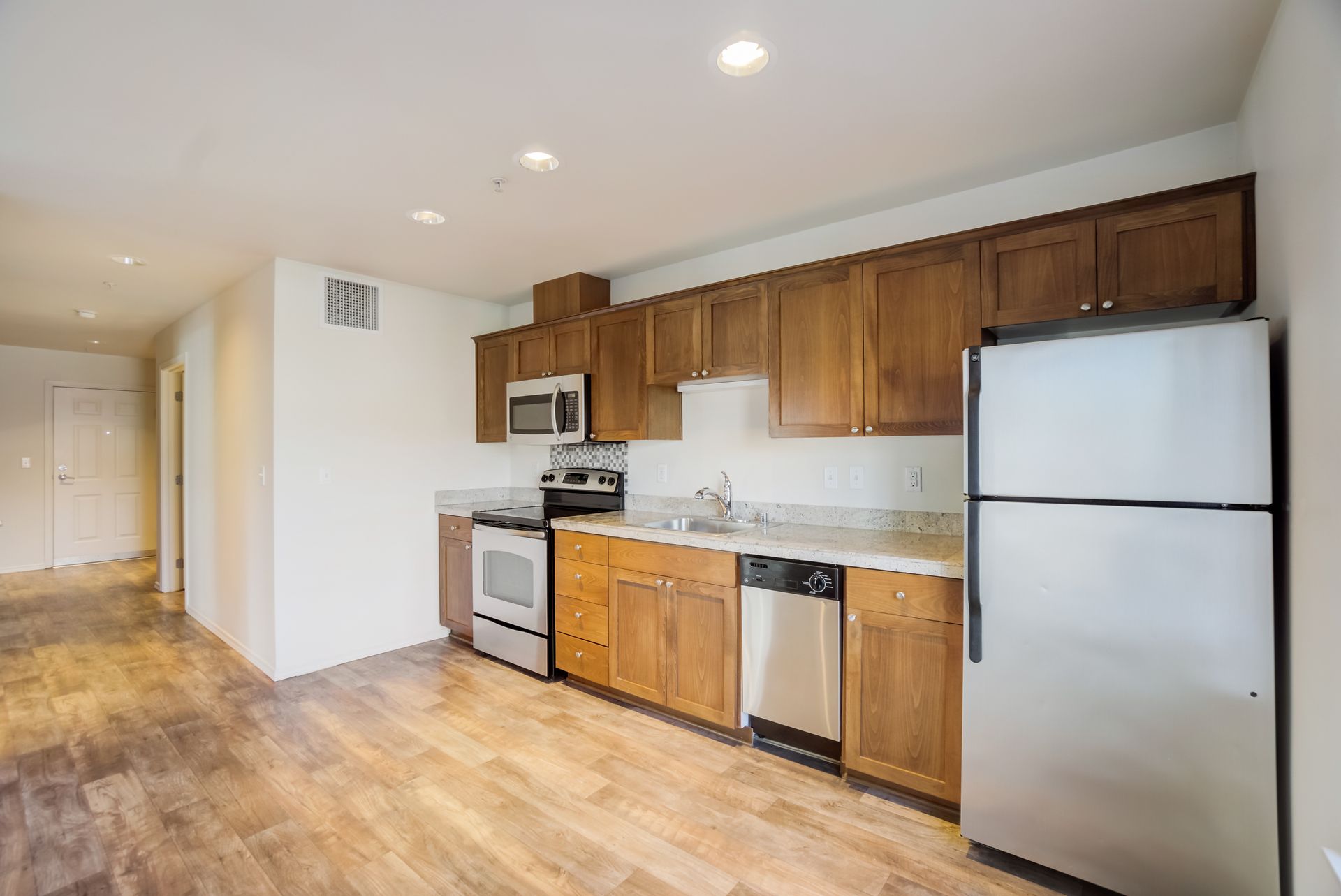 A kitchen with wooden cabinets , stainless steel appliances , and a refrigerator.