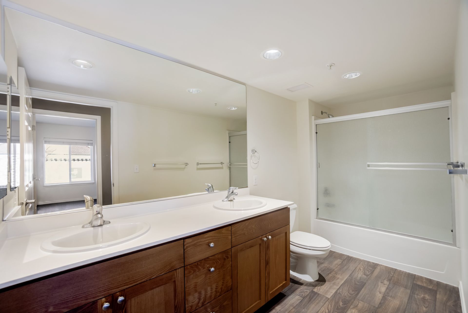A bathroom with two sinks , a toilet , and a large mirror.