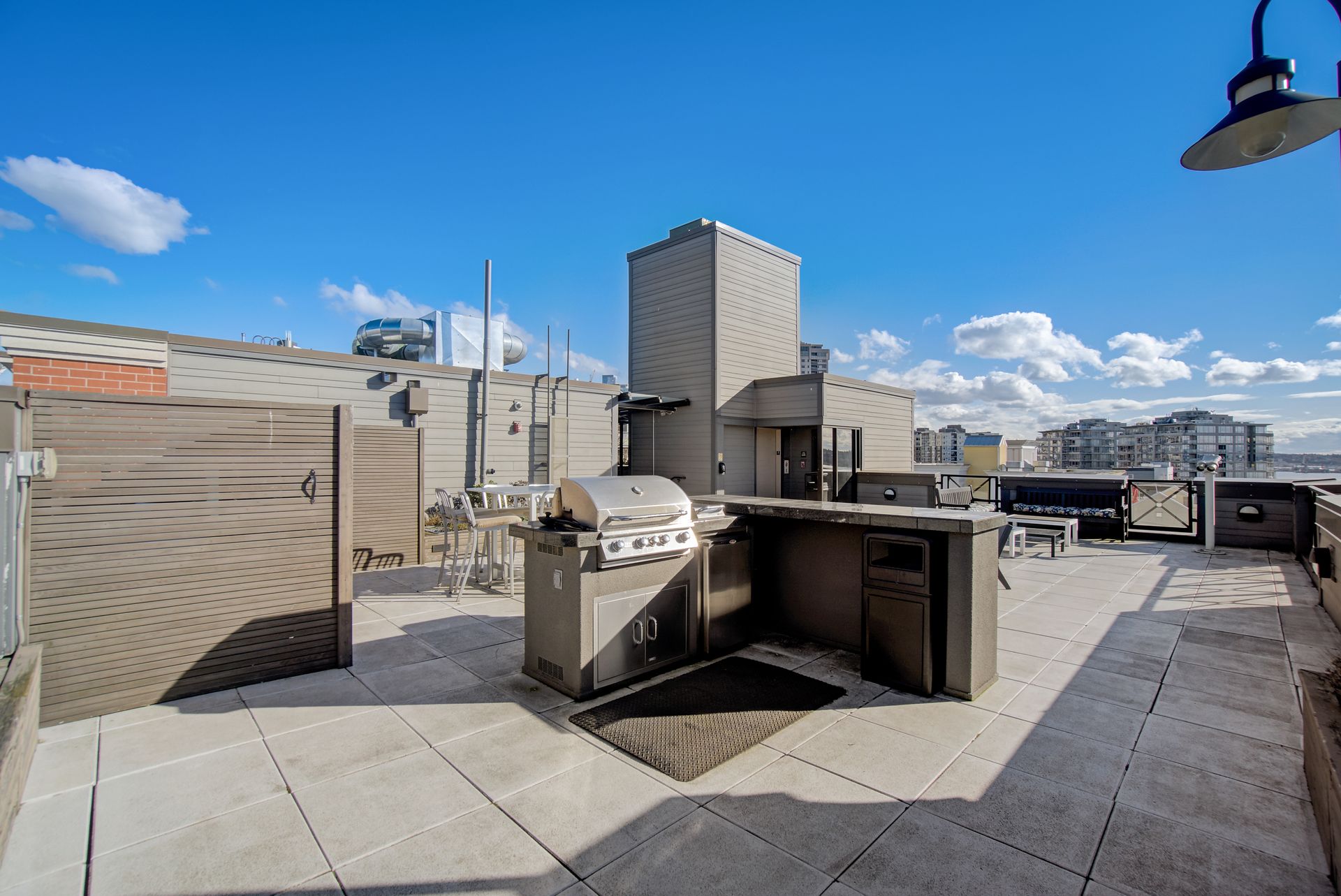 A rooftop patio with a grill and a fence