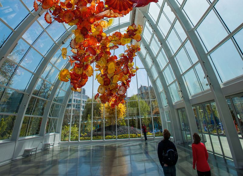 Two people are looking at a sculpture in a glass building.