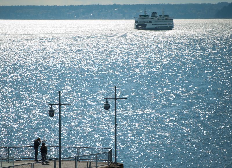 A couple standing on a pier looking at a boat in the water