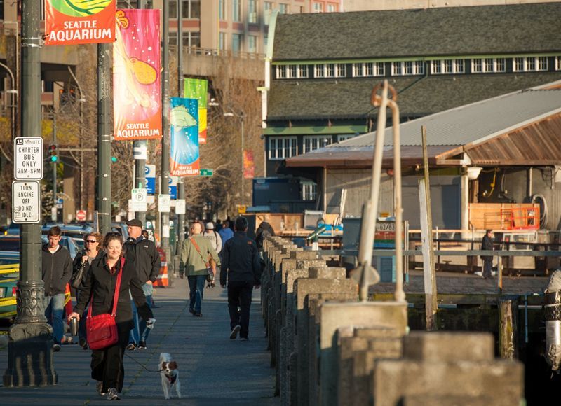 A group of people walking down a sidewalk in front of an aquarium
