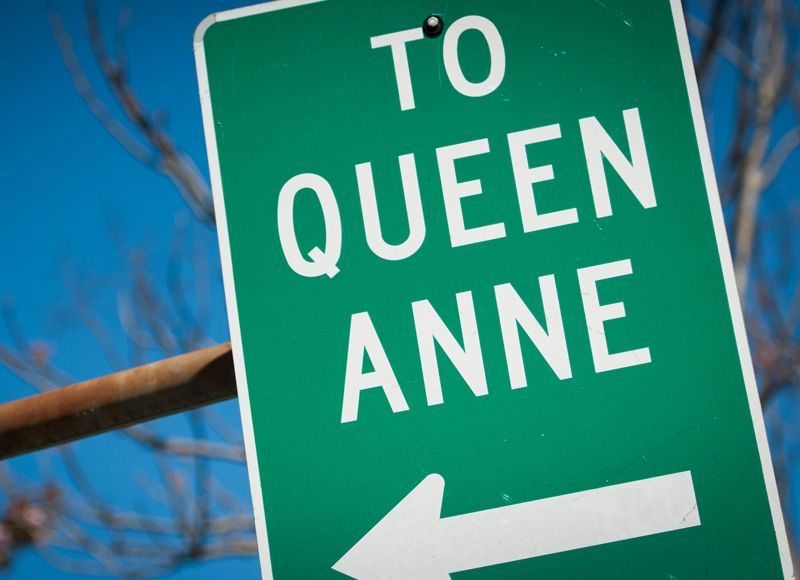 A green street sign points the way to queen anne