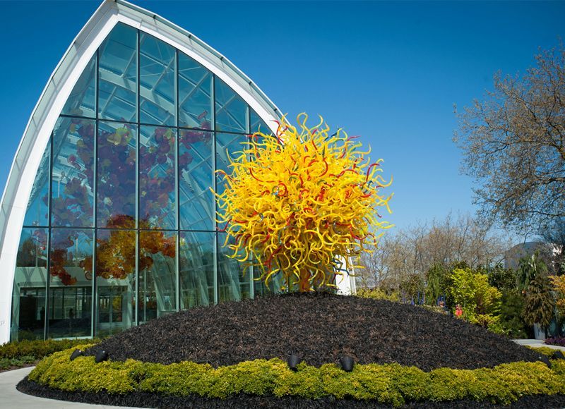 A large glass building with a sculpture in front of it.