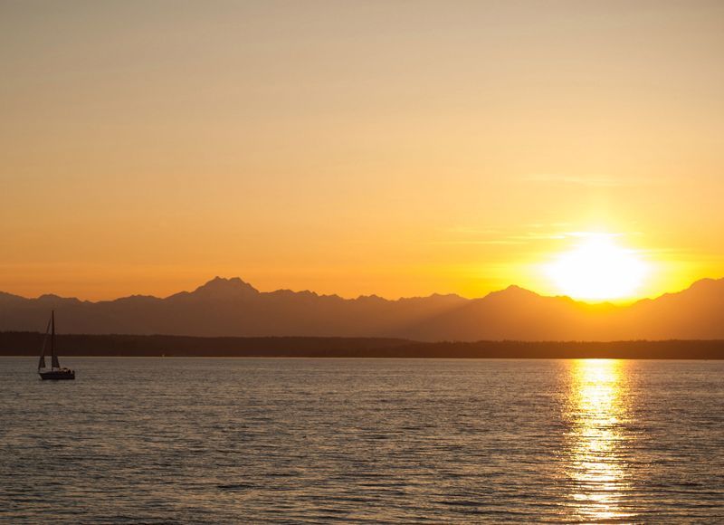 A sunset over a body of water with mountains in the background