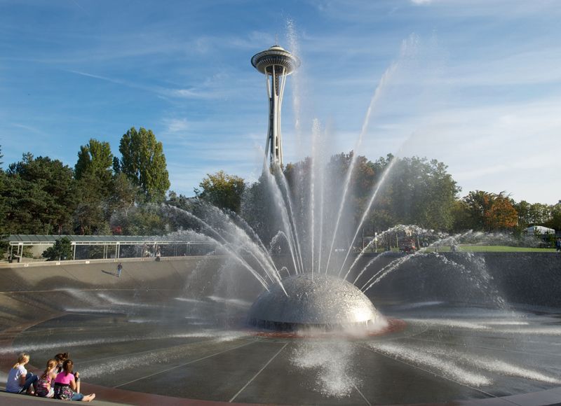 A fountain in a park with the space needle in the background