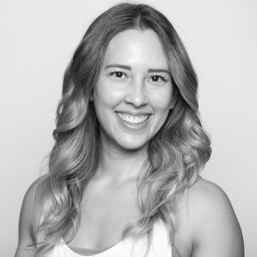 A woman with long hair is smiling in a black and white photo.