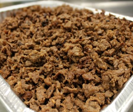 Three tacos topped with fresh pico de gallo and cilantro, served on a white plate on a patterned table.