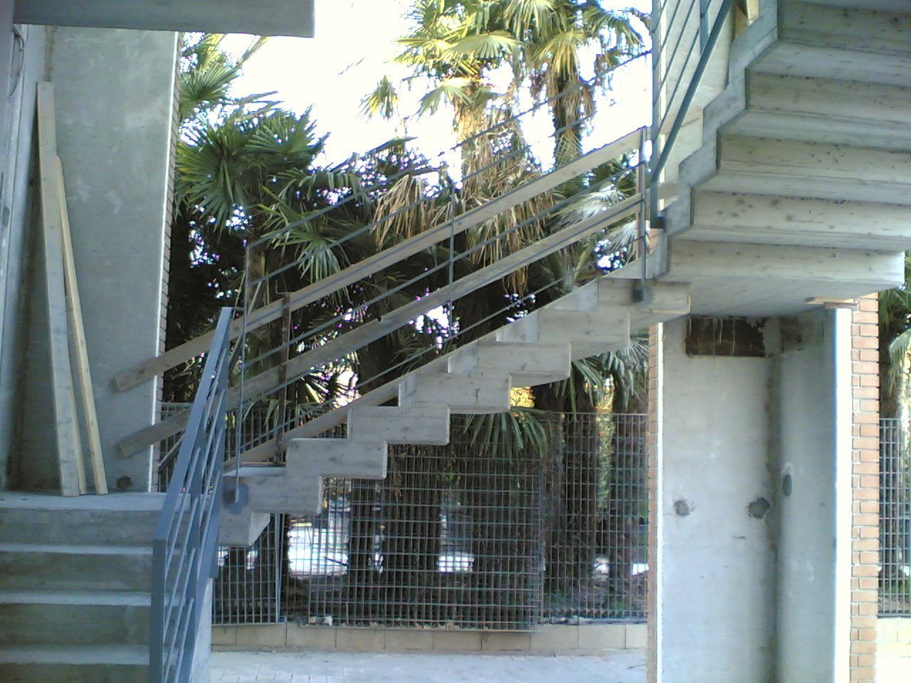 Una scala con una ringhiera metallica e una recinzione sullo sfondo