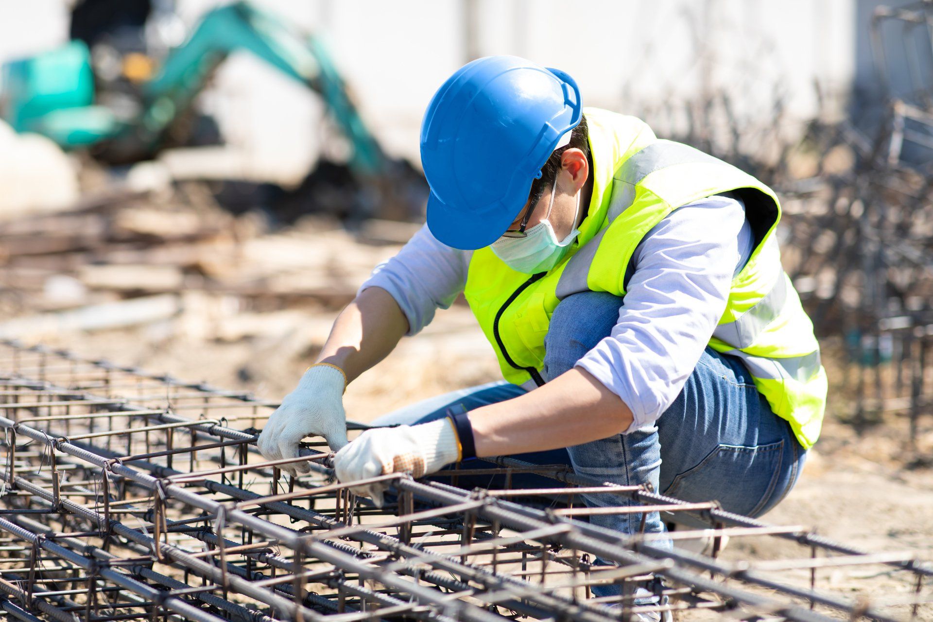 un operaio edile che indossa un elmetto e un giubbotto di sicurezza sta lavorando su una struttura metallica.