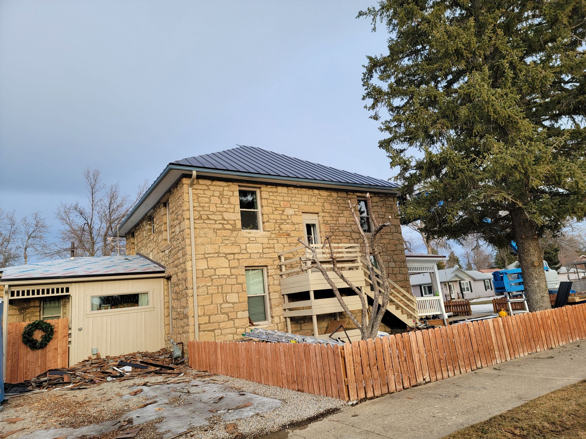 A large stone house with a blue roof is being remodeled.
