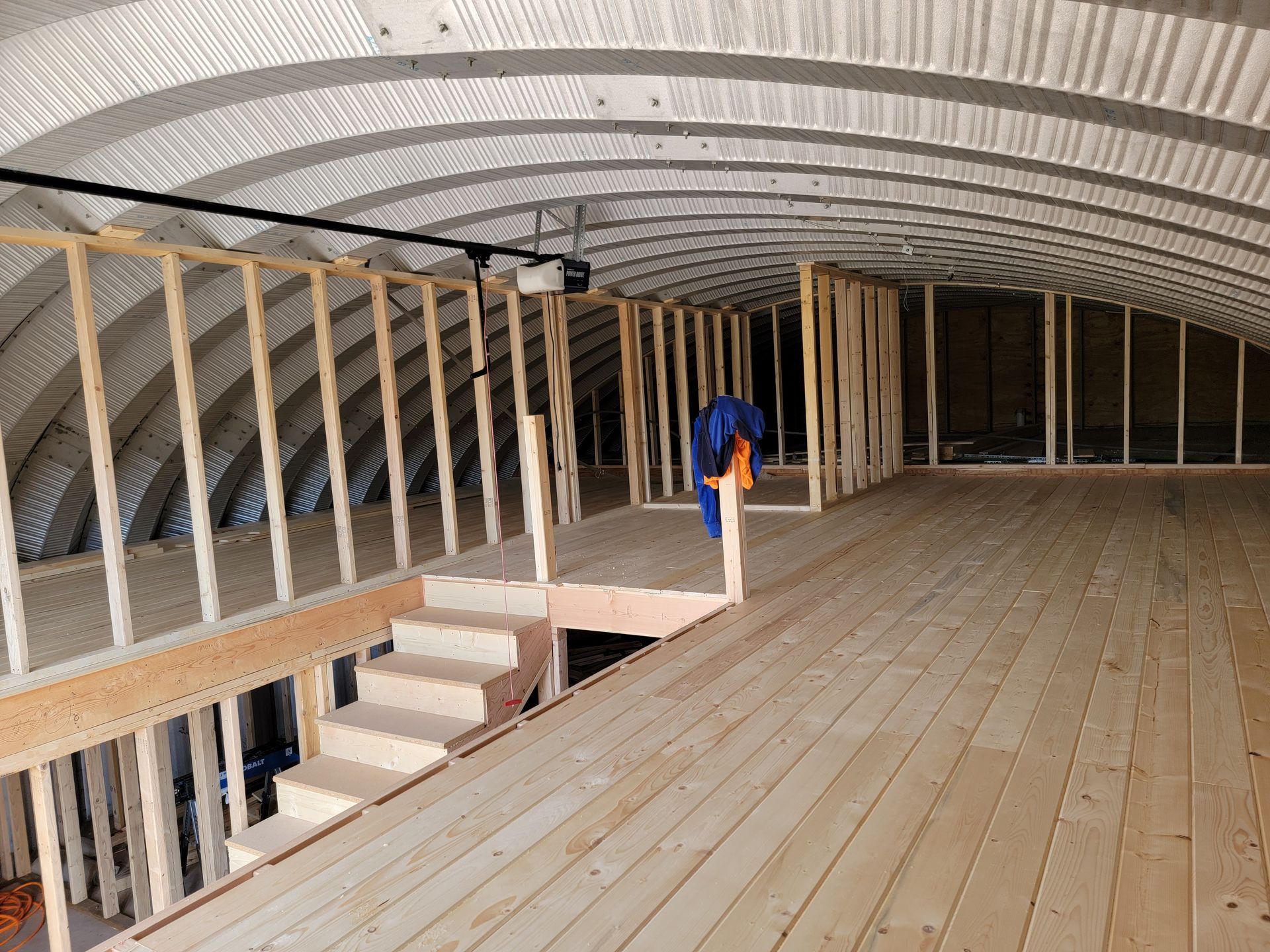 A large room with a wooden floor and stairs.