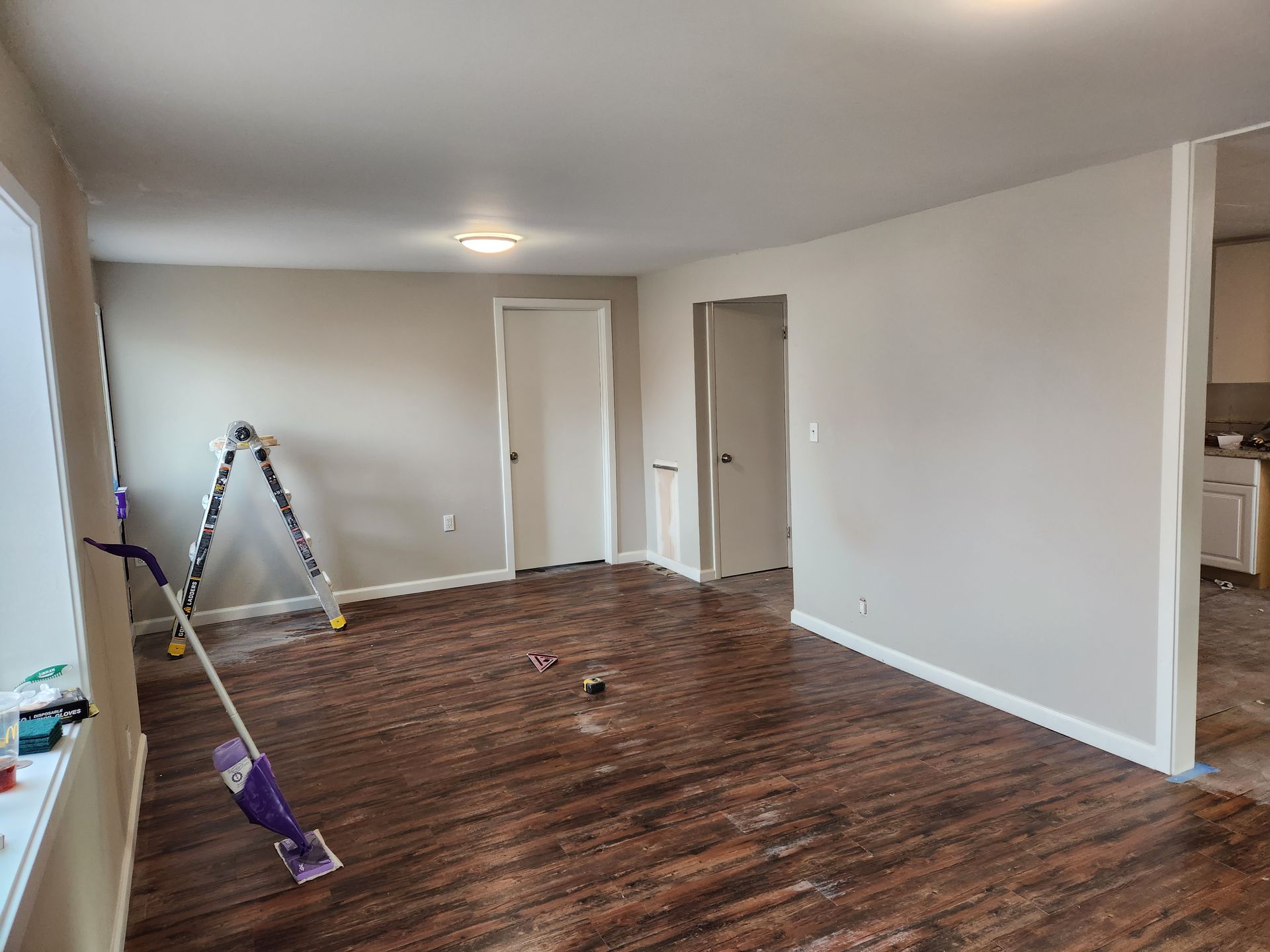 An empty living room with hardwood floors and a mop.