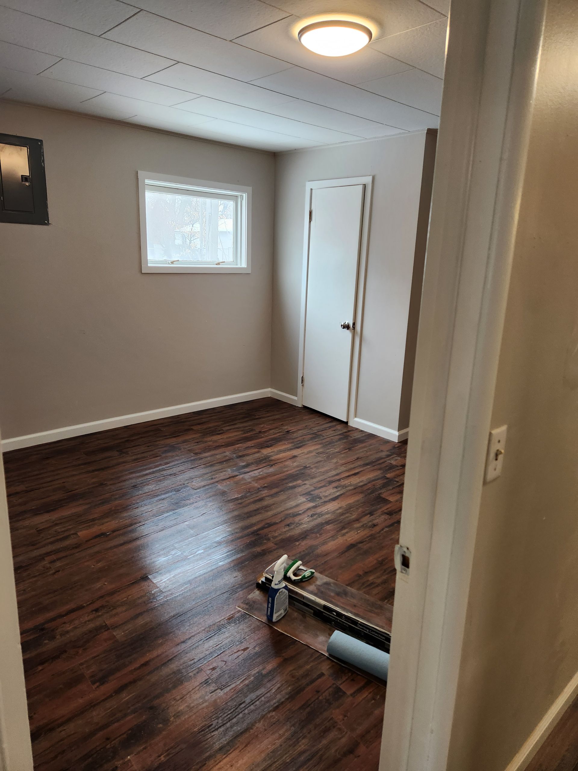 An empty room with hardwood floors and a window.