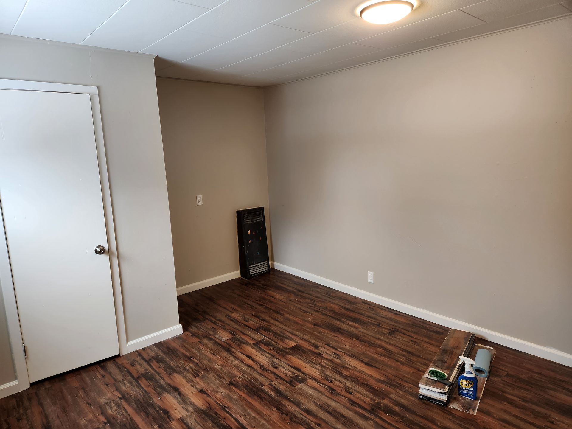 An empty room with hardwood floors and a door.