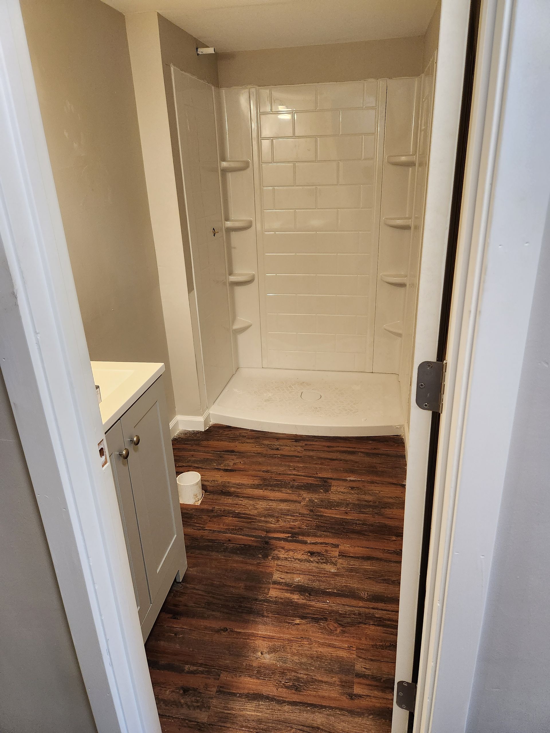A bathroom with a walk in shower and a wooden floor.