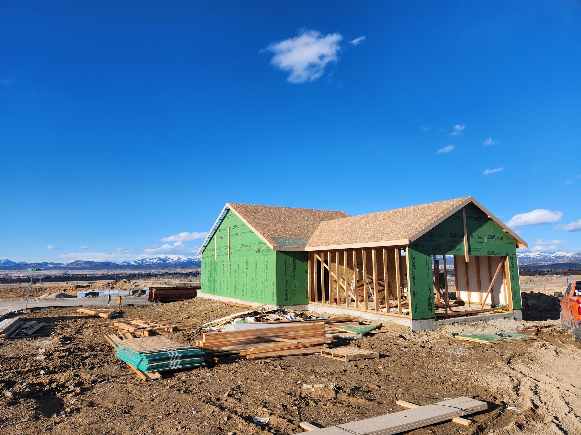 A house is being built in a dirt field with mountains in the background.