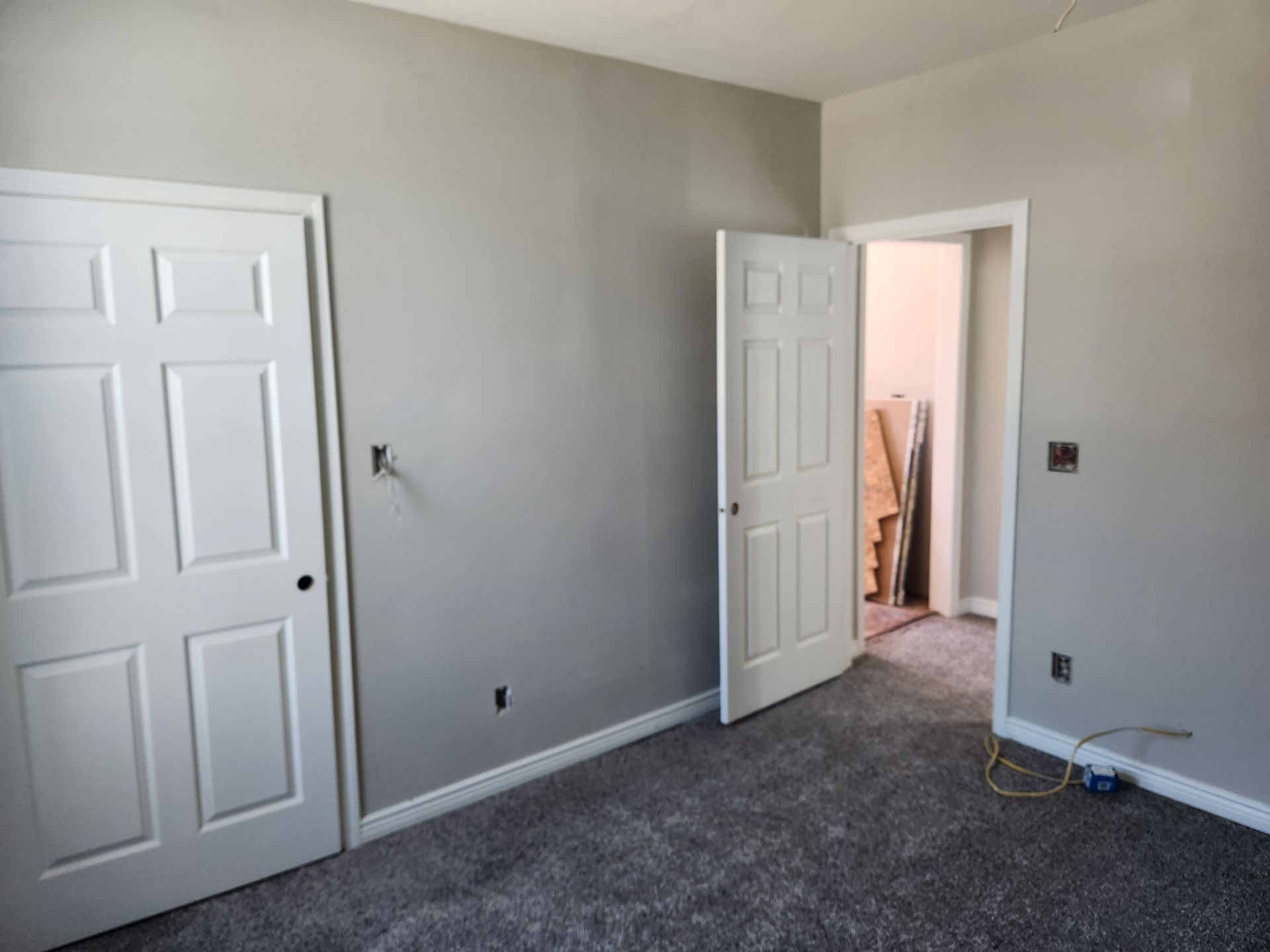 An empty bedroom with gray walls and a carpeted floor.