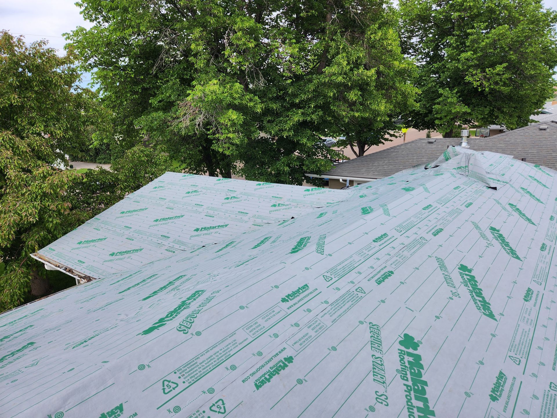 A roof with a lot of green sheets on it and trees in the background.