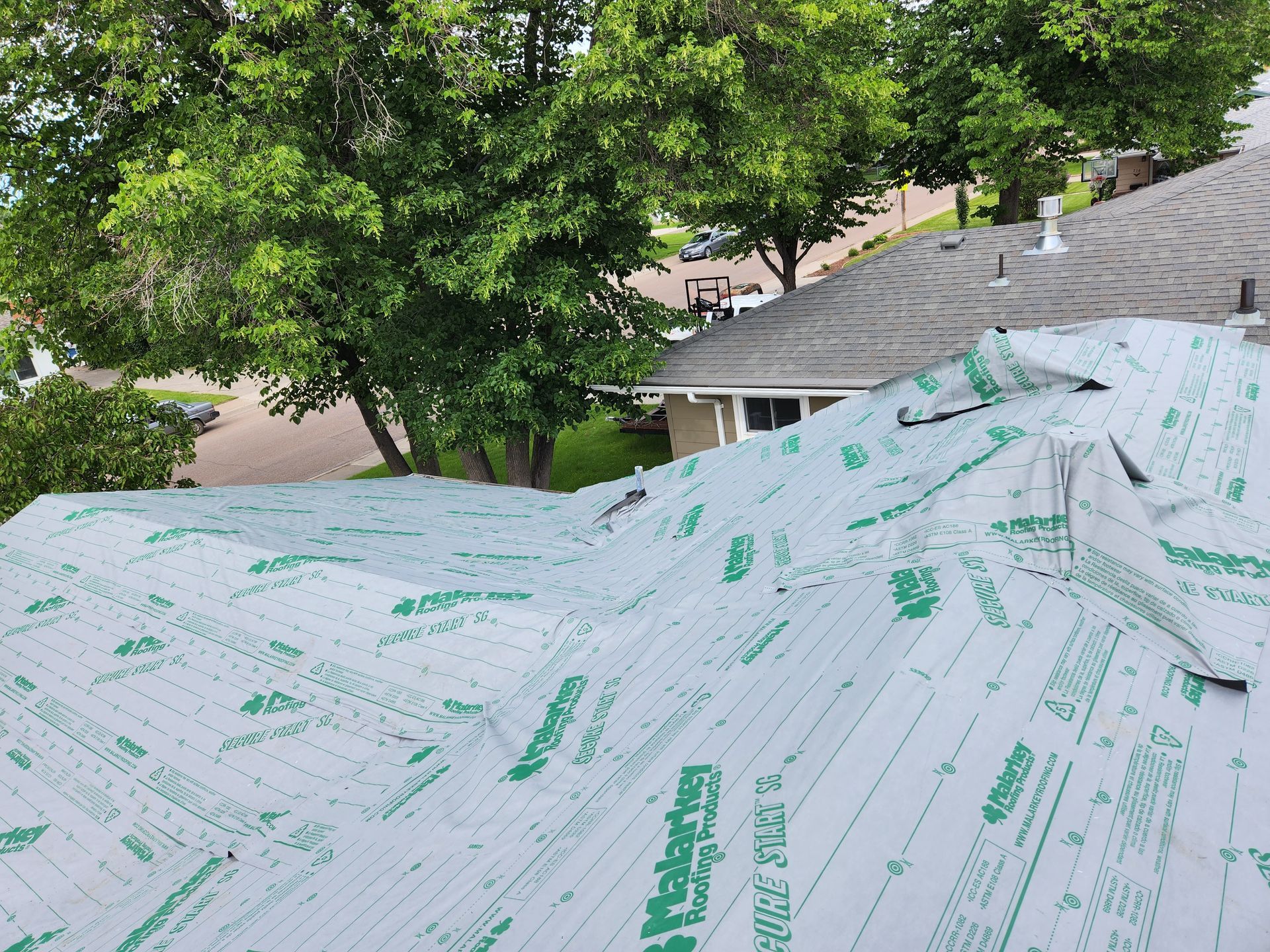 The roof of a house is being covered with a roofing material.