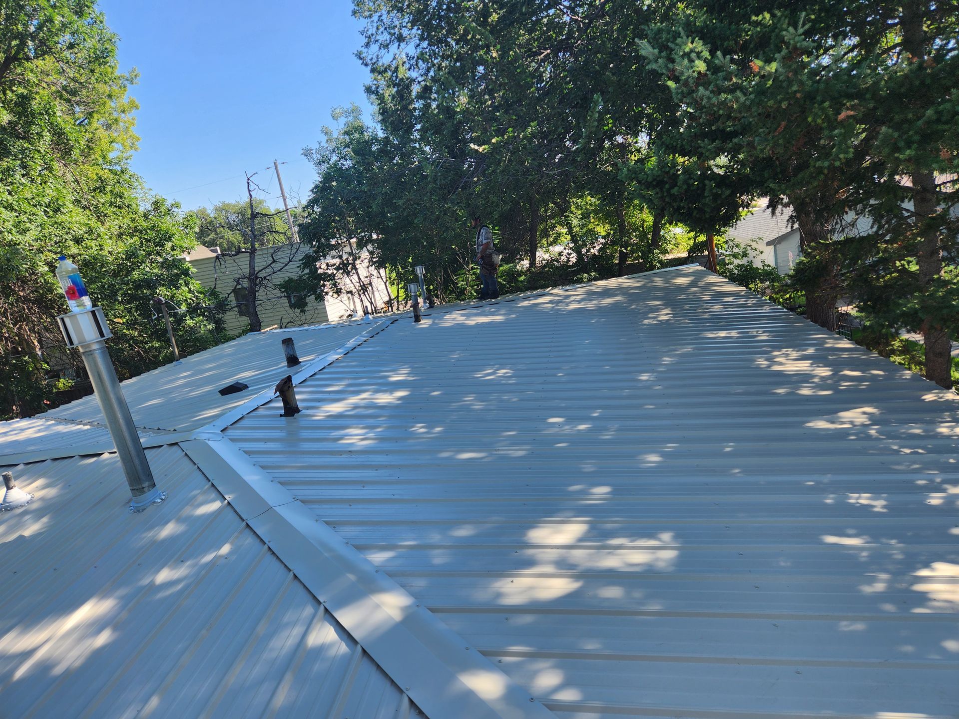 A roof with a chimney on it and trees in the background.