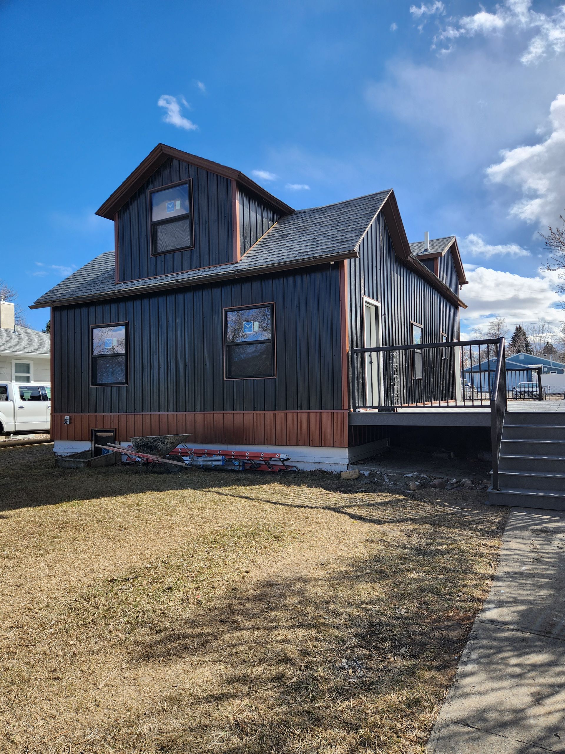 A large black house with a deck and stairs in front of it.