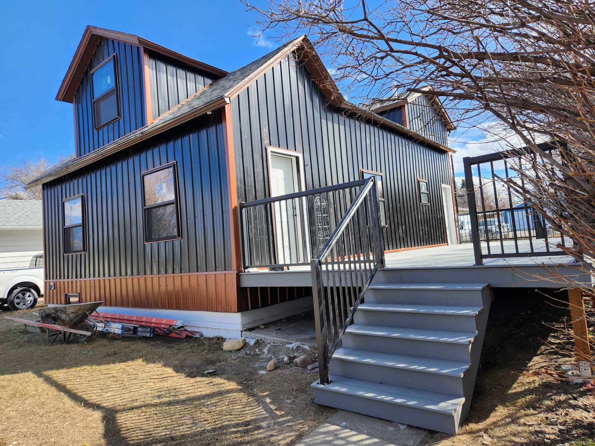 A black house with a deck and stairs in front of it.