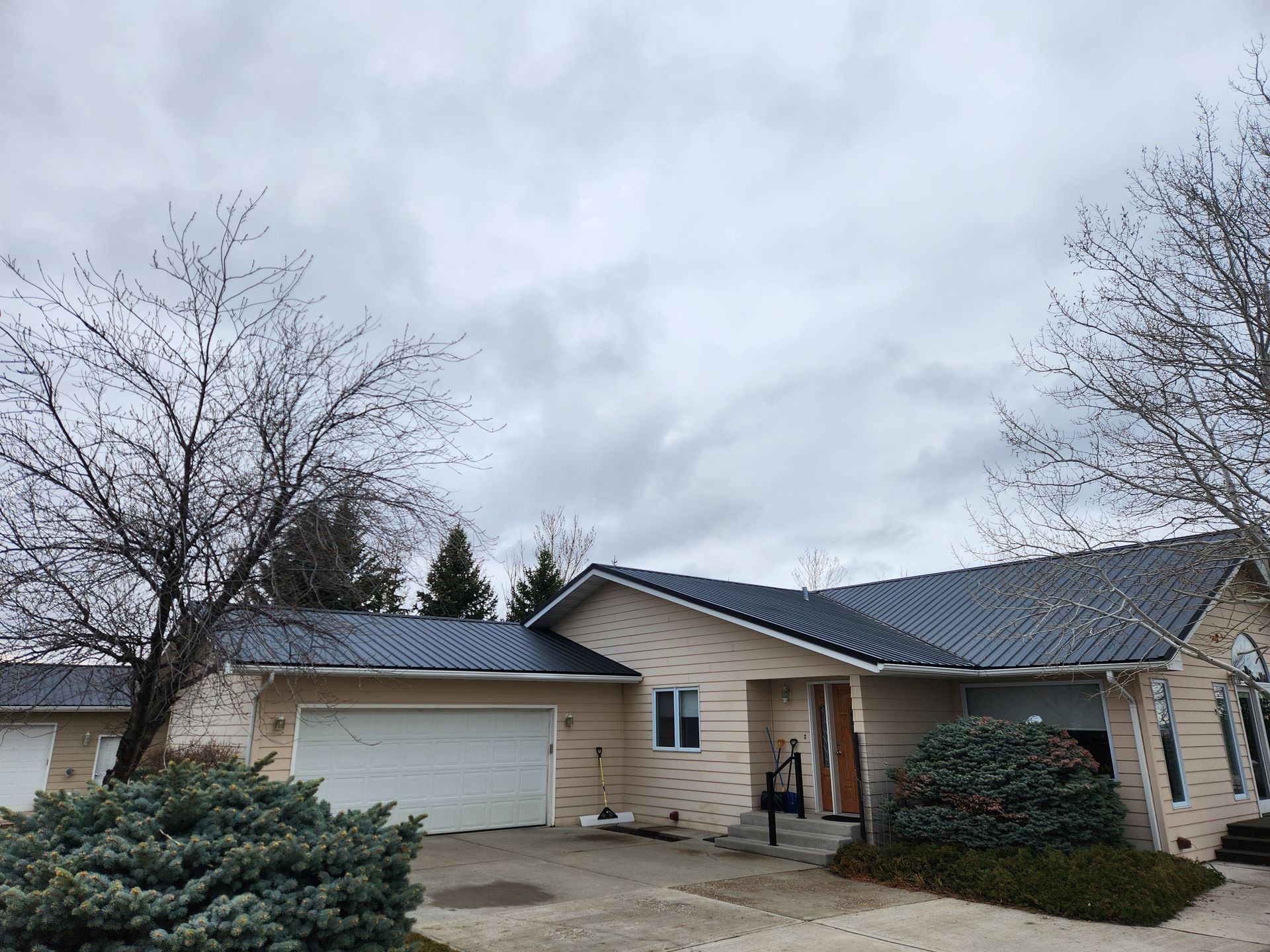 A house with a blue roof and a garage on a cloudy day.
