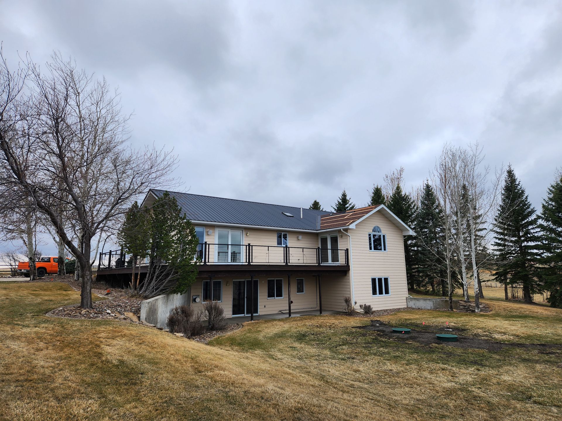 A large white house with a blue roof is sitting on top of a grassy hill.