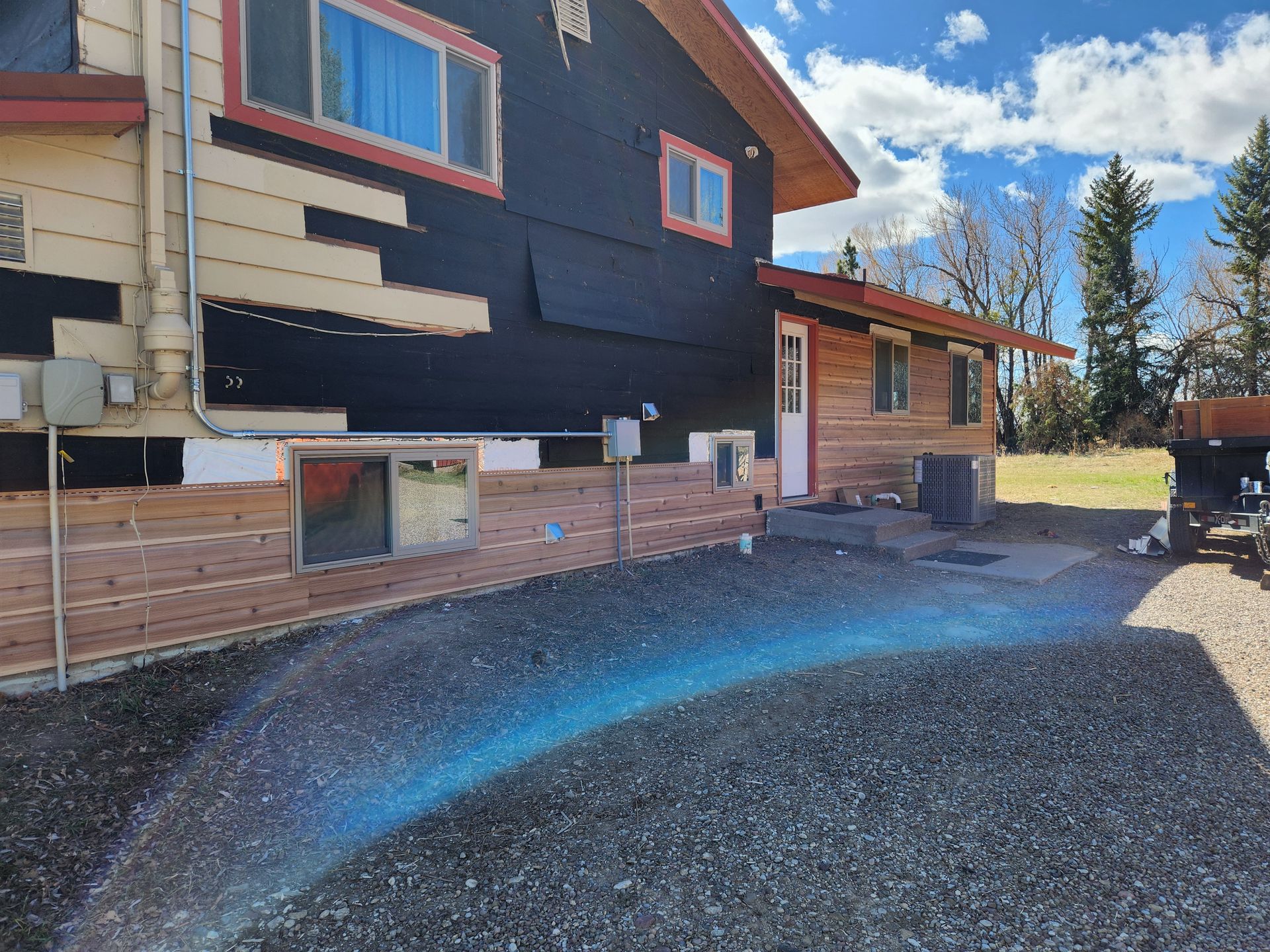 A large house with a lot of windows is sitting on top of a gravel lot.