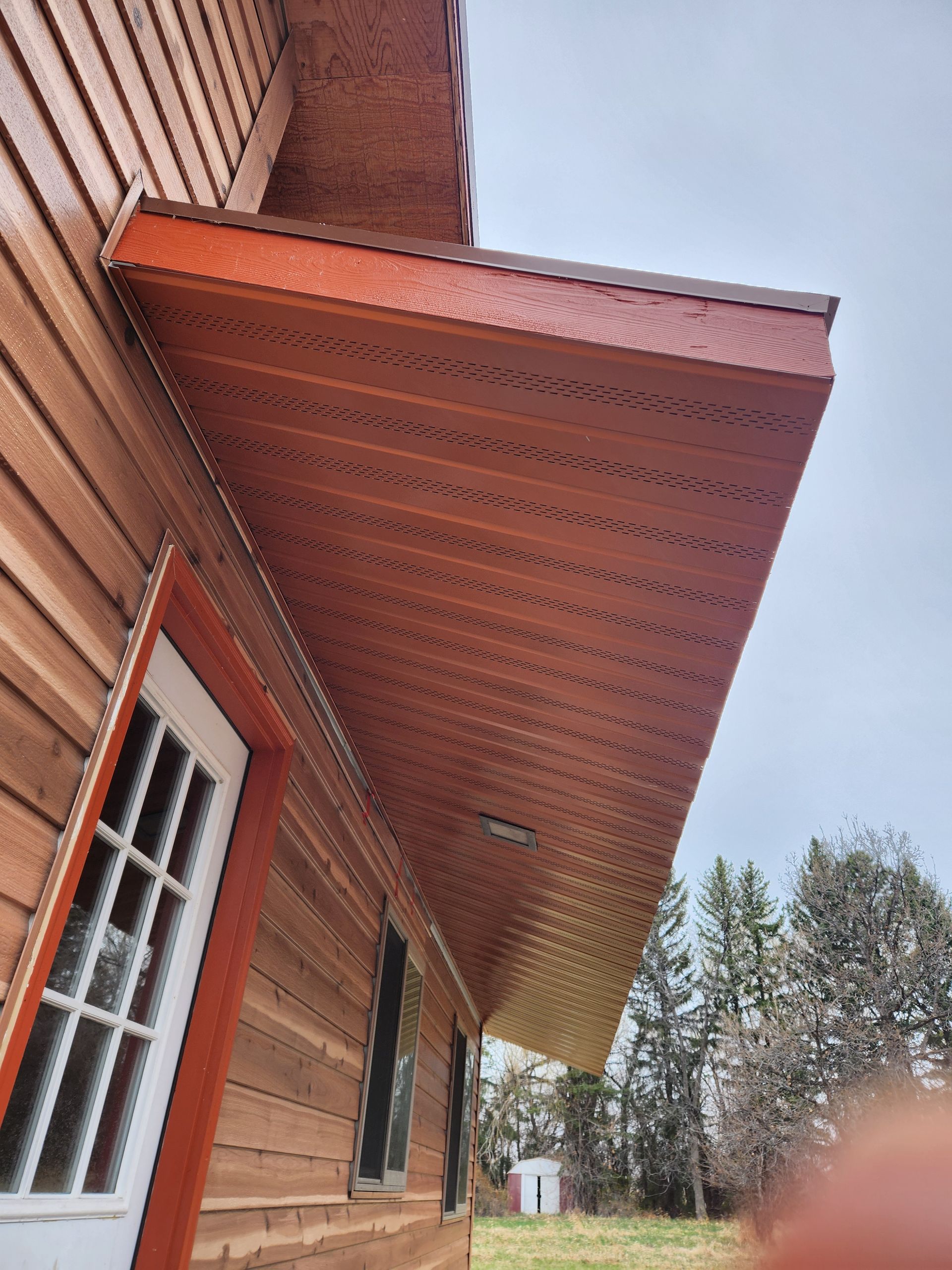 A wooden house with a red roof and a white door