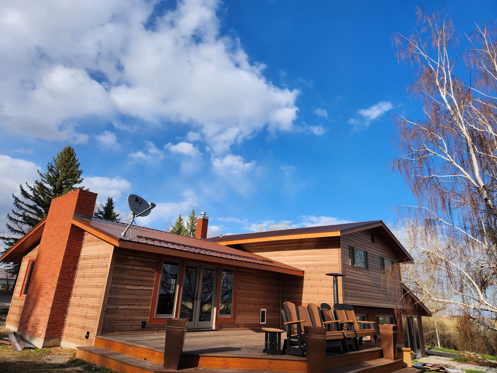 A large wooden house with a large deck and a satellite dish on the roof.