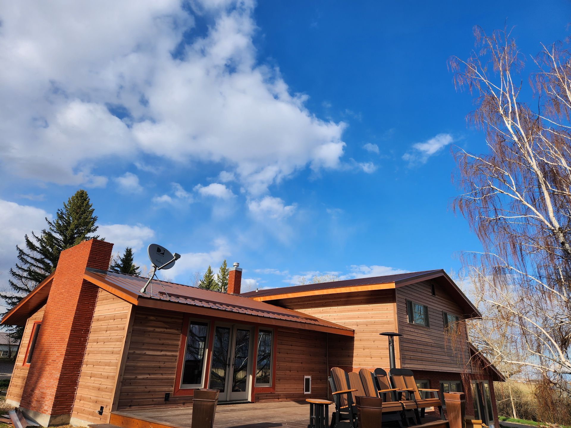 A large wooden house with a satellite dish on the roof.