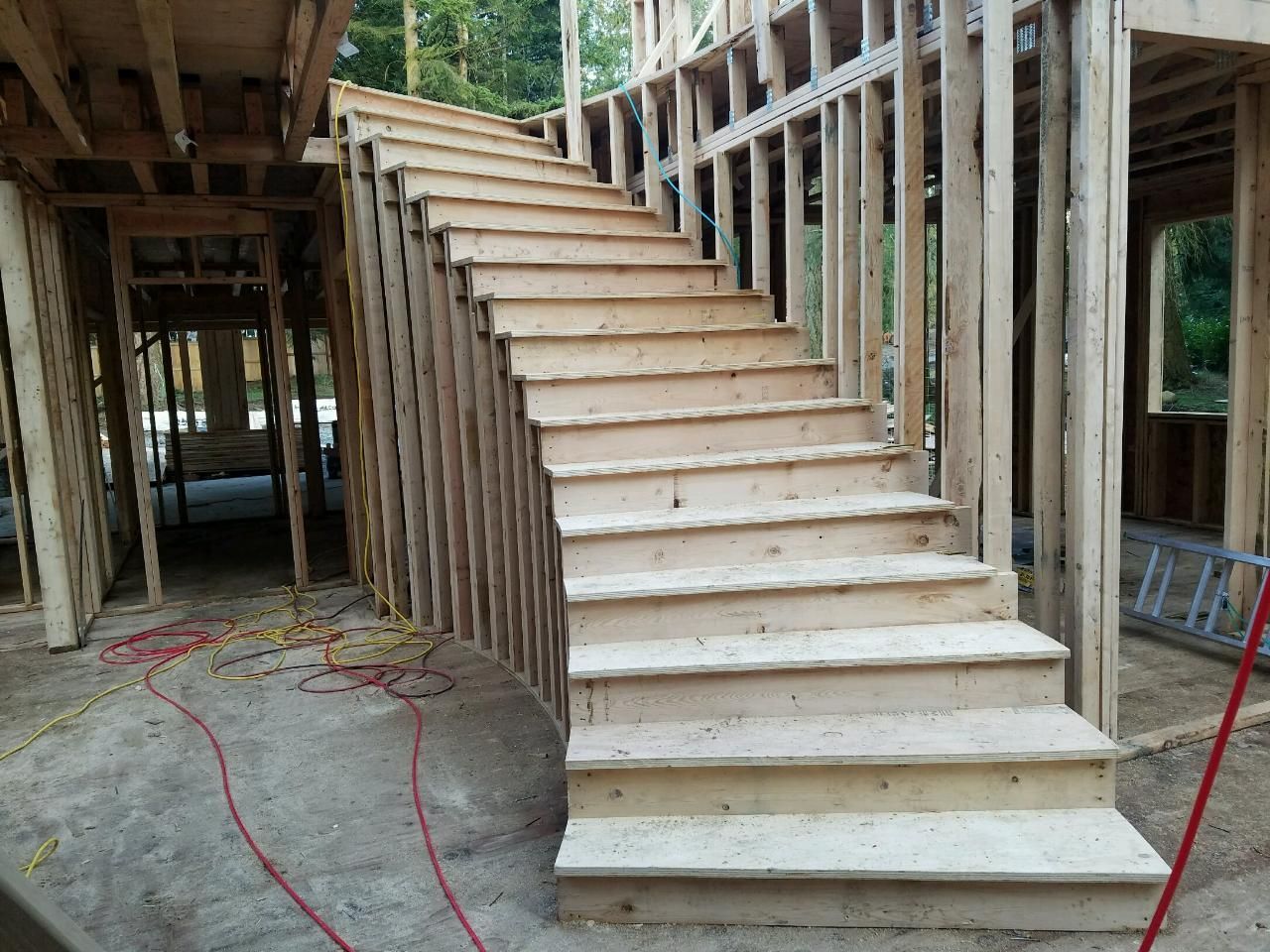 A wooden staircase is being built in a house under construction.
