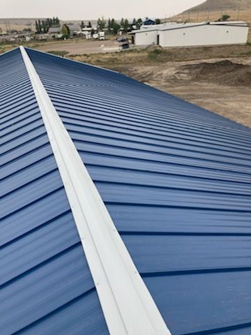 A blue metal roof with a white trim is being installed on a building.