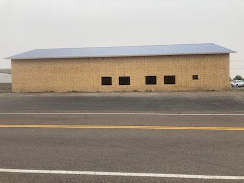 A large wooden building with a metal roof is sitting next to a road.