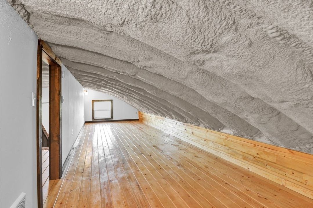 An empty attic with a wooden floor and a white ceiling.
