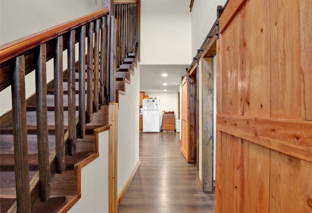 A hallway with stairs and a sliding barn door