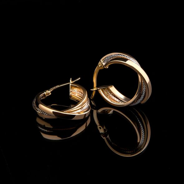 A pair of gold hoop earrings on a black surface