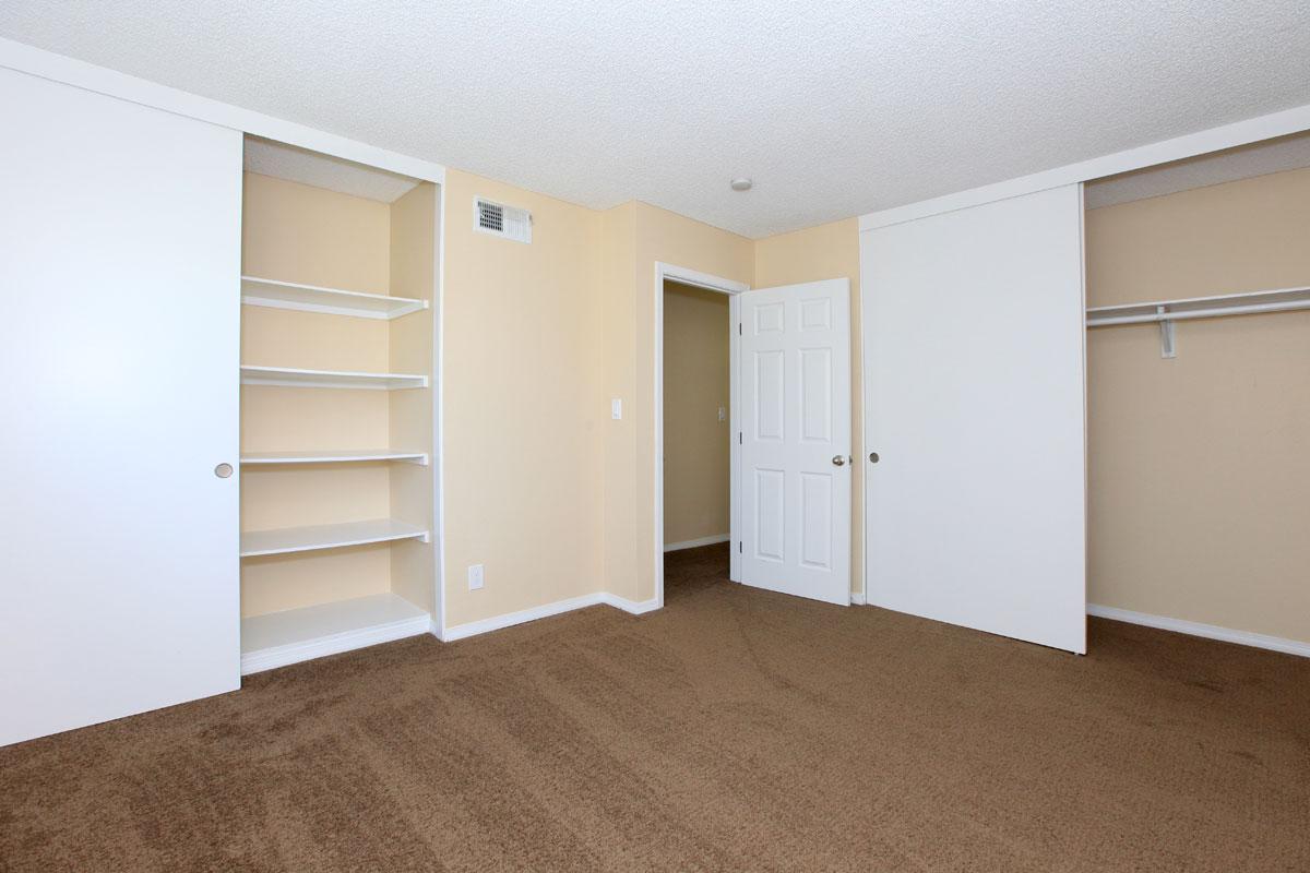 Bedroom with carpet, a closet, and shelves.