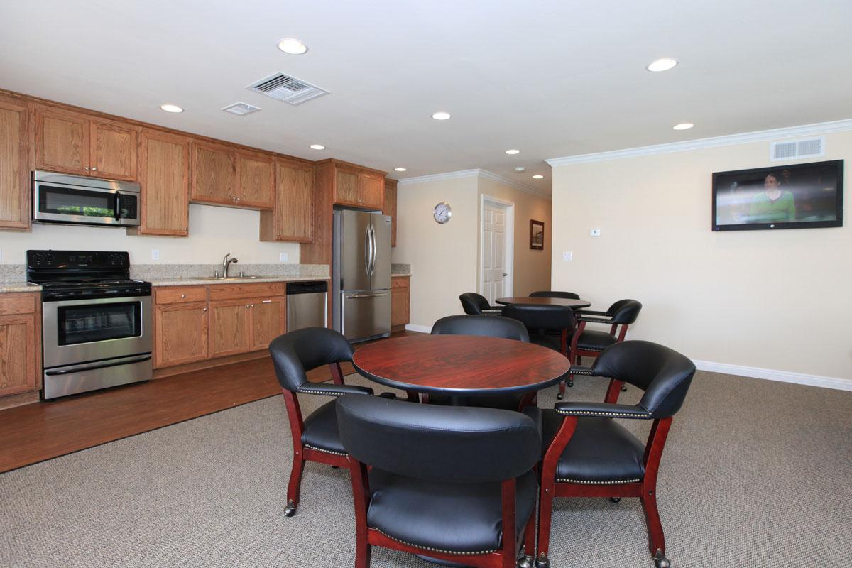 Community room with a full kitchen, tables, and a television.