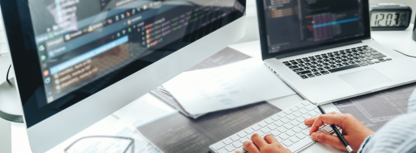 A person is designing a website on two computer monitors