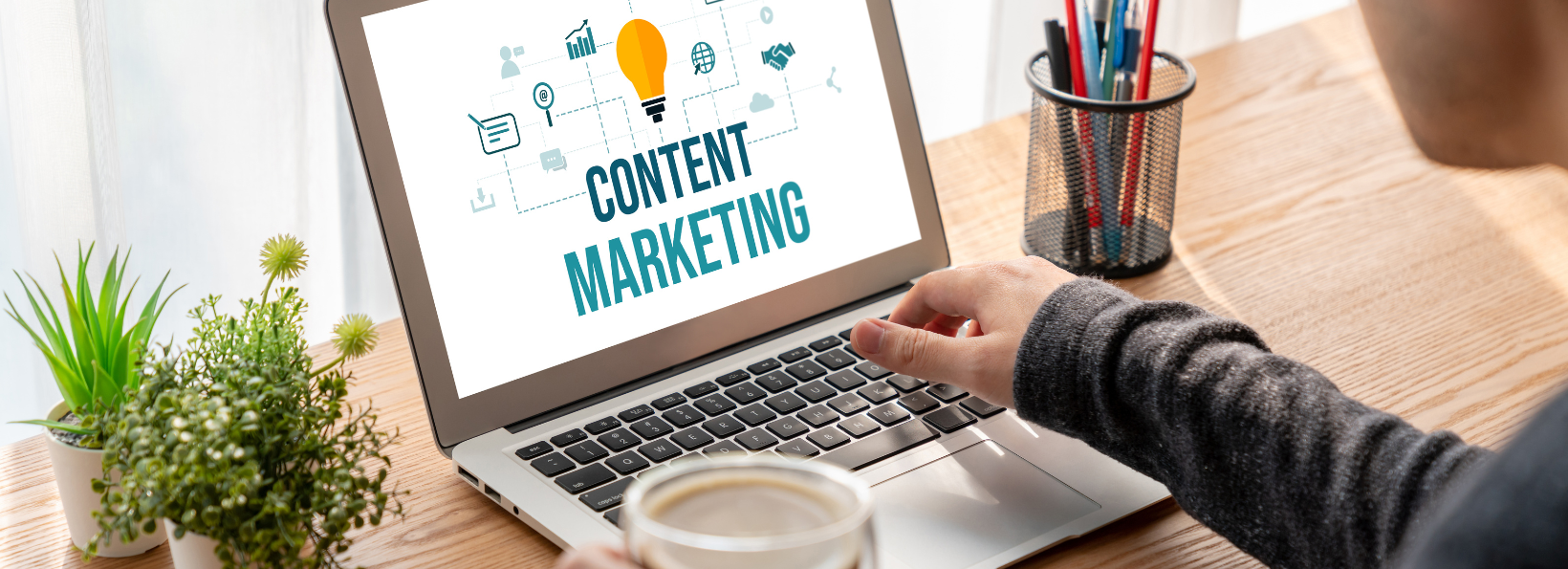 A person is typing on a laptop with the words content marketing on the screen.