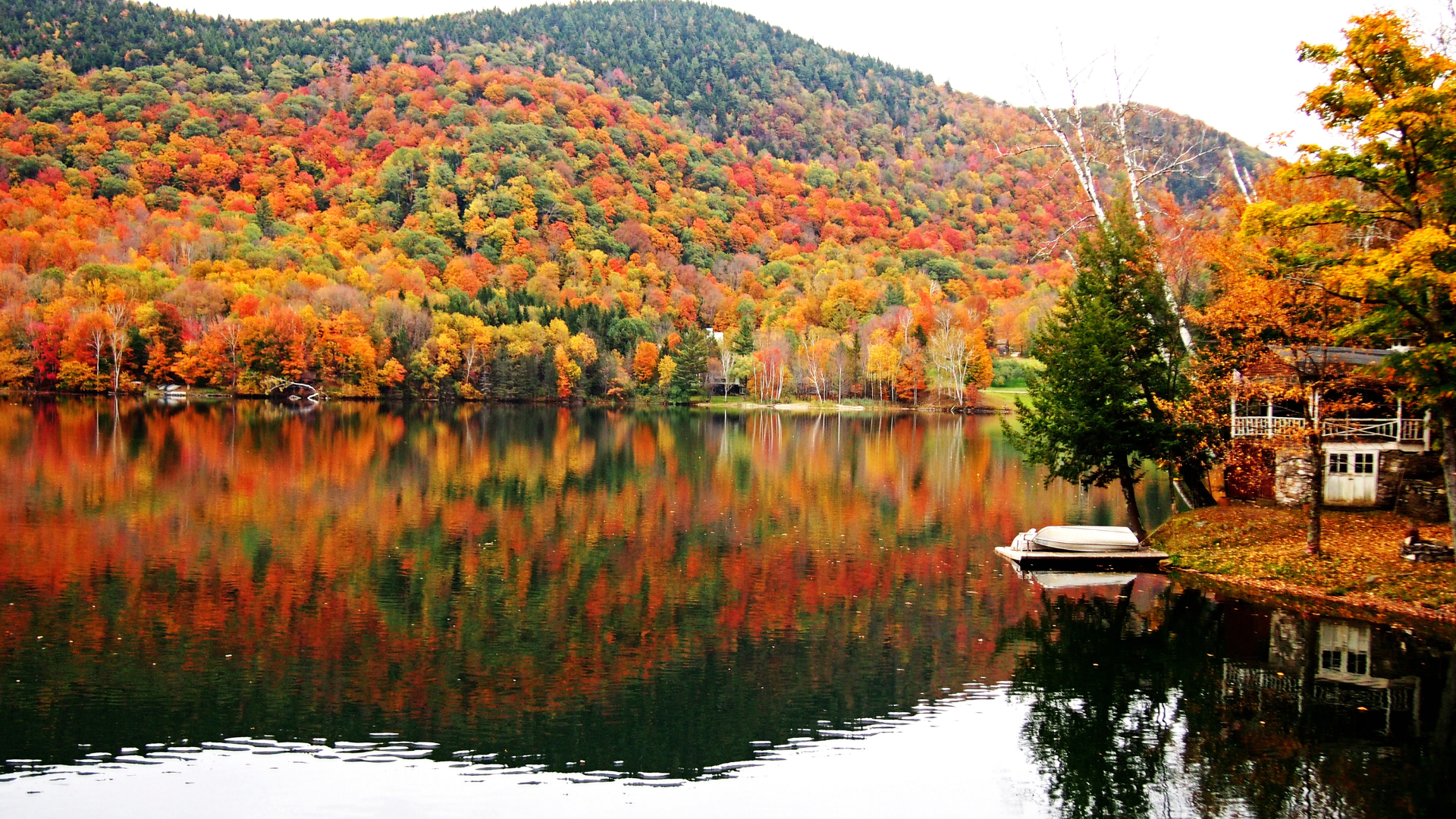 Colorful mountain range reflecting on a lake in Vermont's Northeast Kingdom during the fall.