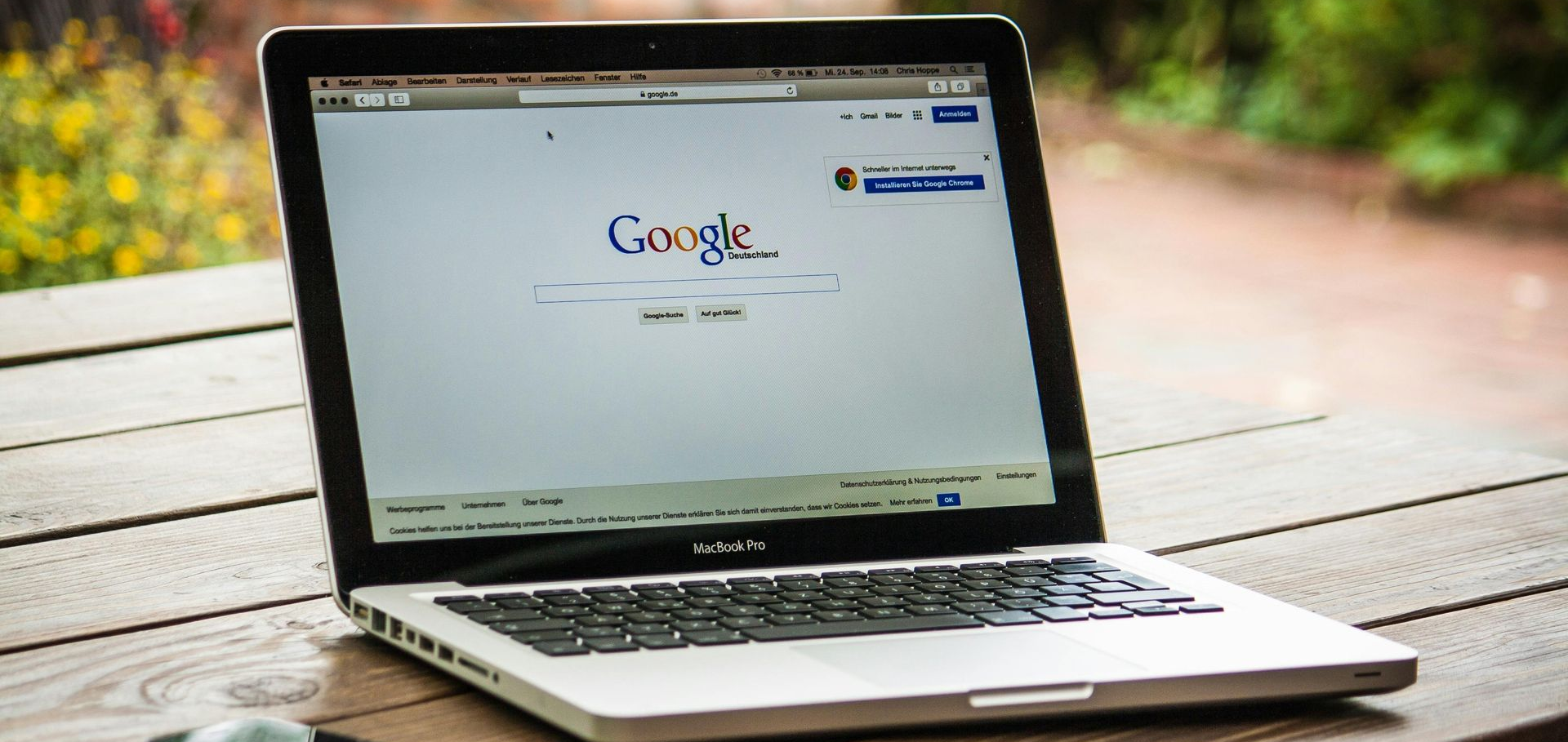 Laptop on wooden table displays the Google search engine.
